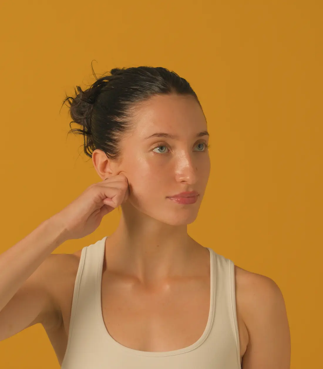 A woman gliding her knuckles down her cheek during a lymphatic drainage session